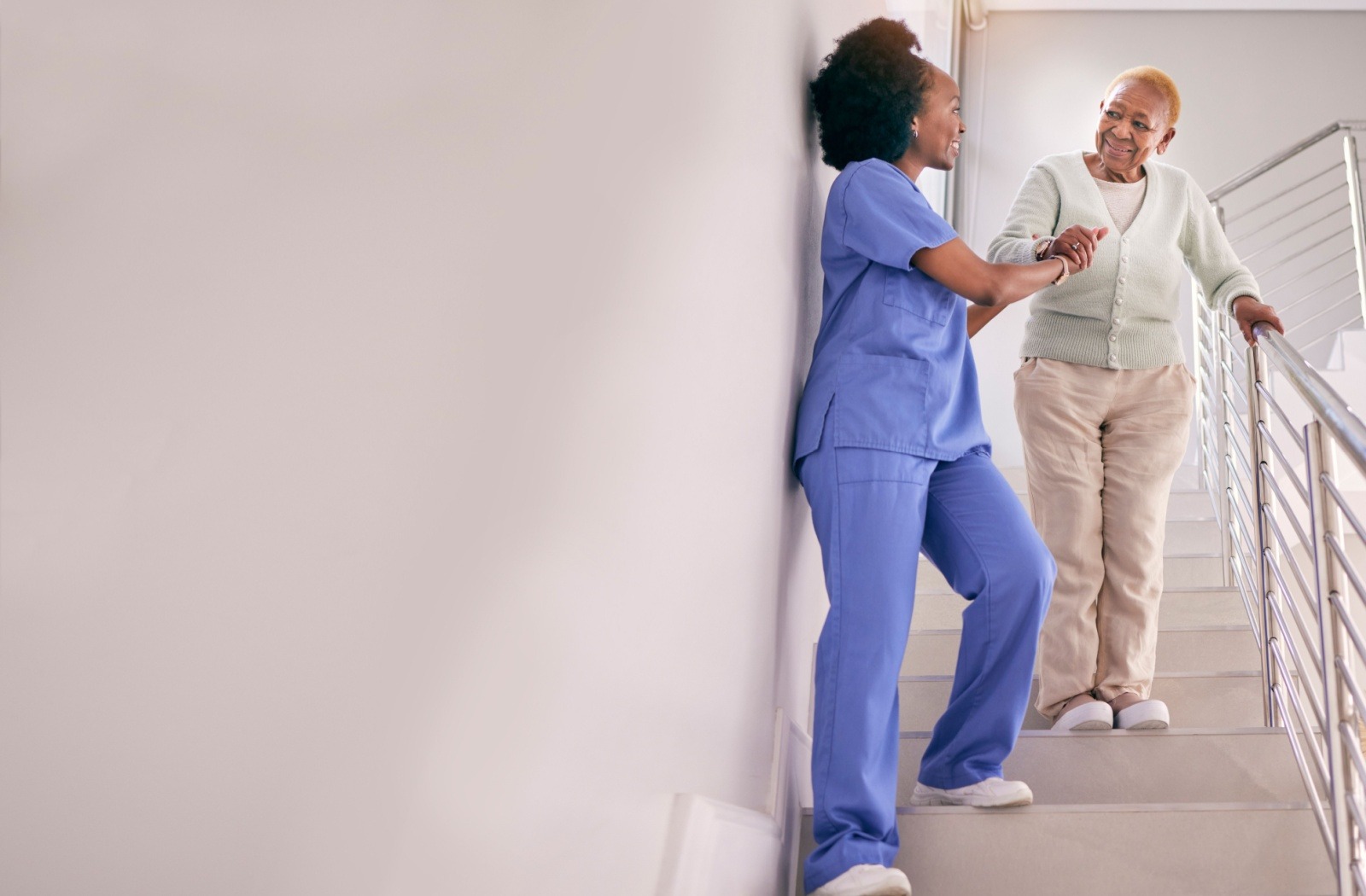 A caregiver assists a resident down a flight of stairs.
