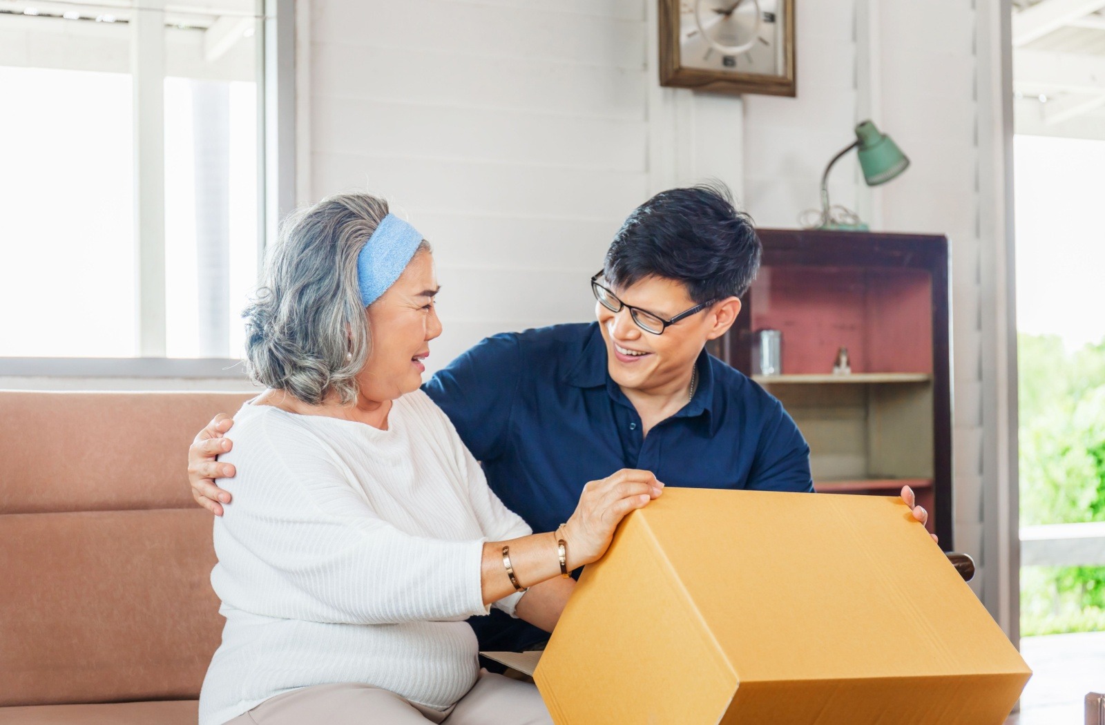 An adult child helps their senior parent with packing moving boxes.

